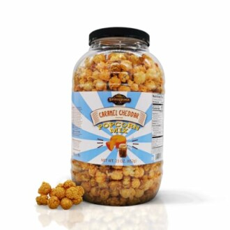 Jar of caramel cheddar popcorn mix with a few pieces outside.